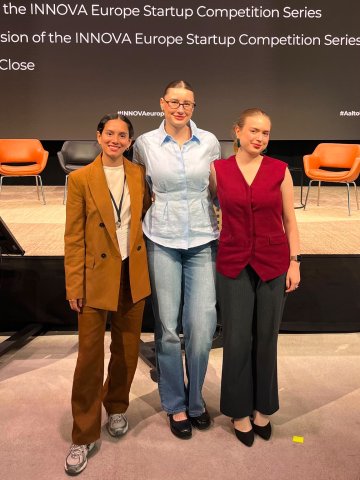 ESMT Berlin Master in Innovation and Entrepreneurship students Jasmin Mantwill, Laura Ruiz, and Gwyneth-Tyger Carys Neumann in front of a presentation board at the Innova conference