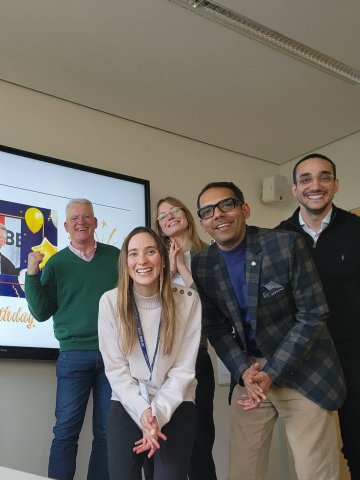 A team of ESMT Berlin Full-time MBA students (Class of 2026) and their mentor during their capstone project. They are celebrating a birthday in a meeting room.