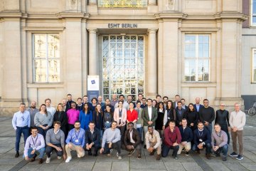 The ESMT Berlin Part-time MBA Class of 2027 having their picture taken outside the main campus entrance