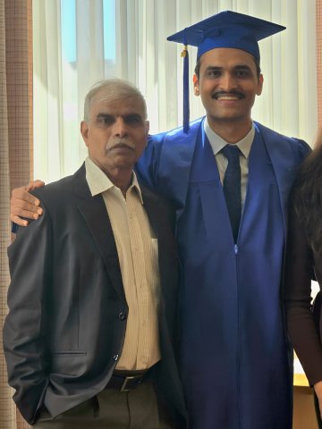 Full-time MBA student Punit Thakkar in his cap and gown on graduation day. He is standing with his family.