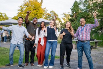 A group of ESMT Berlin Global Online MBA students smiling in the campus garden during Berlin Experience Week