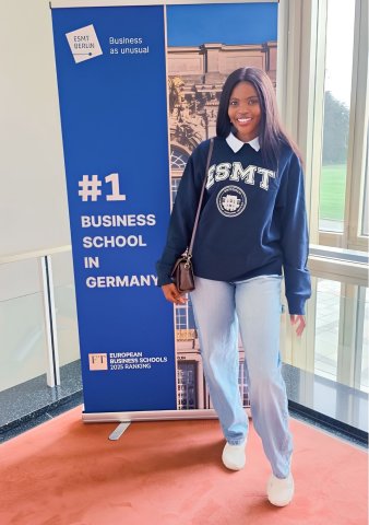 Portrait of ESMT Berlin Global Online MBA student Joan Mwaniki smiling for the camera in an ESMT-branded sweatshirt