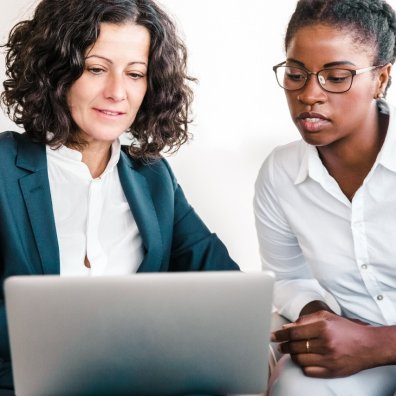Executive coach and coachee look together at a laptop screen