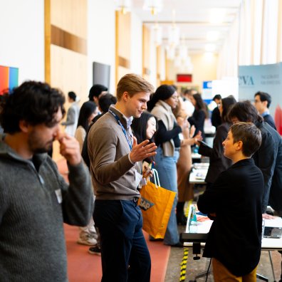The ESMT Berlin Career Fair. There are several students talking to people and looking at booths