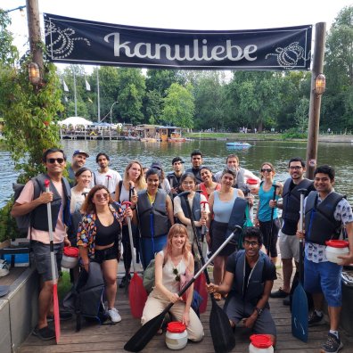 Participants at the ESMT student event Bergfest getting ready for a group canoeing trip. They are standing on a dock in front of boats and smiling.