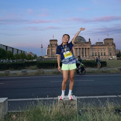 ESMT Berlin student Ting Han posing in front of the Berlin Reichstag during a relay with the EMST Running Club