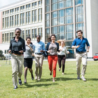 Six students running towards the camra on a green field. 