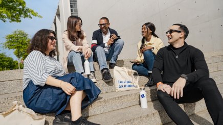 Full-time MBA student Gloria Mopotu and students from ESMT Berlin sitting on stairs 