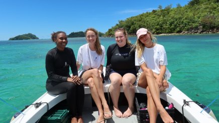 ESMT Berlin Master in Global Management students on a Social Impact Project trip to the Seychelles. They are sitting on a boat in a tropical bay