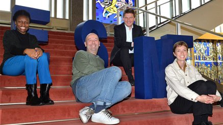 4 people sitting on stairs with the ESMT letters 