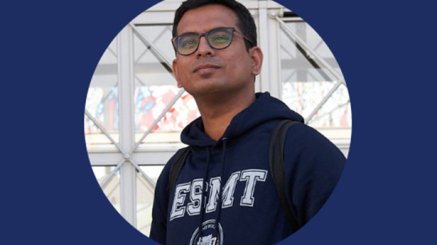Aparajith Raman standing in front of the ESMT building wearing ESMT hoodie