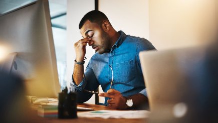 Tired man sitting in front of computer monitor. 