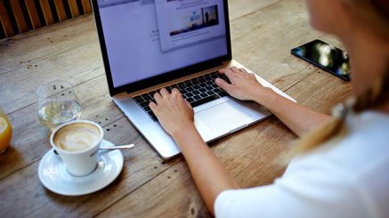 Back view of young successful female freelancer use net-book for distance work during her recreation time, woman's hands keyboarding on portable laptop computer with blank copy space on the screen