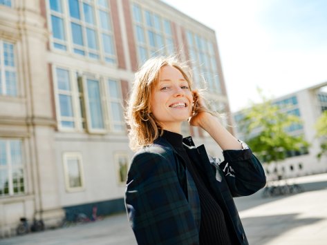 Picture of Johanne Björklund Larsen, an ESMT Berlin Full-time MBA student, standing outside the campus building in the sunshine and smiling. 