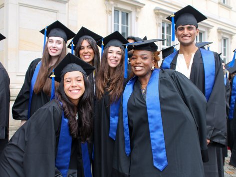 Students from the ESMT Berlin master's class at graduation in their gowns. They are all hugging and smiling