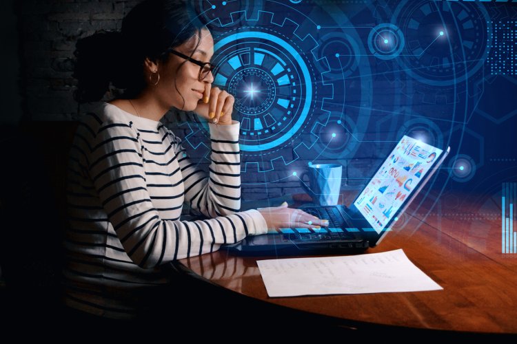 woman sitting at desk working on laptop with digital graphics surrounding her