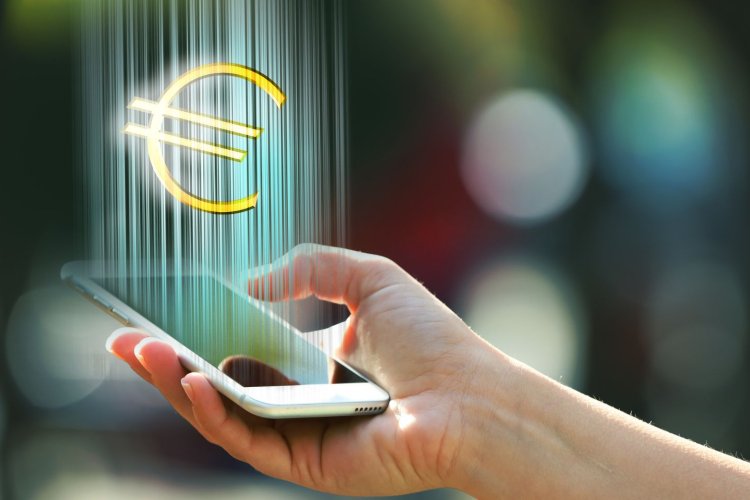 Hand holding a mobile phone with euro sign outdoors, on blurred background