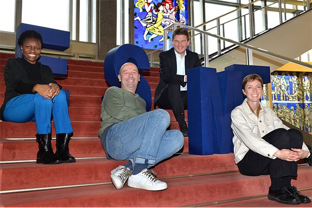 4 people sitting on stairs with the ESMT letters 