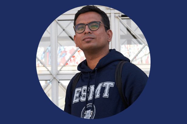 Aparajith Raman standing in front of the ESMT building wearing ESMT hoodie