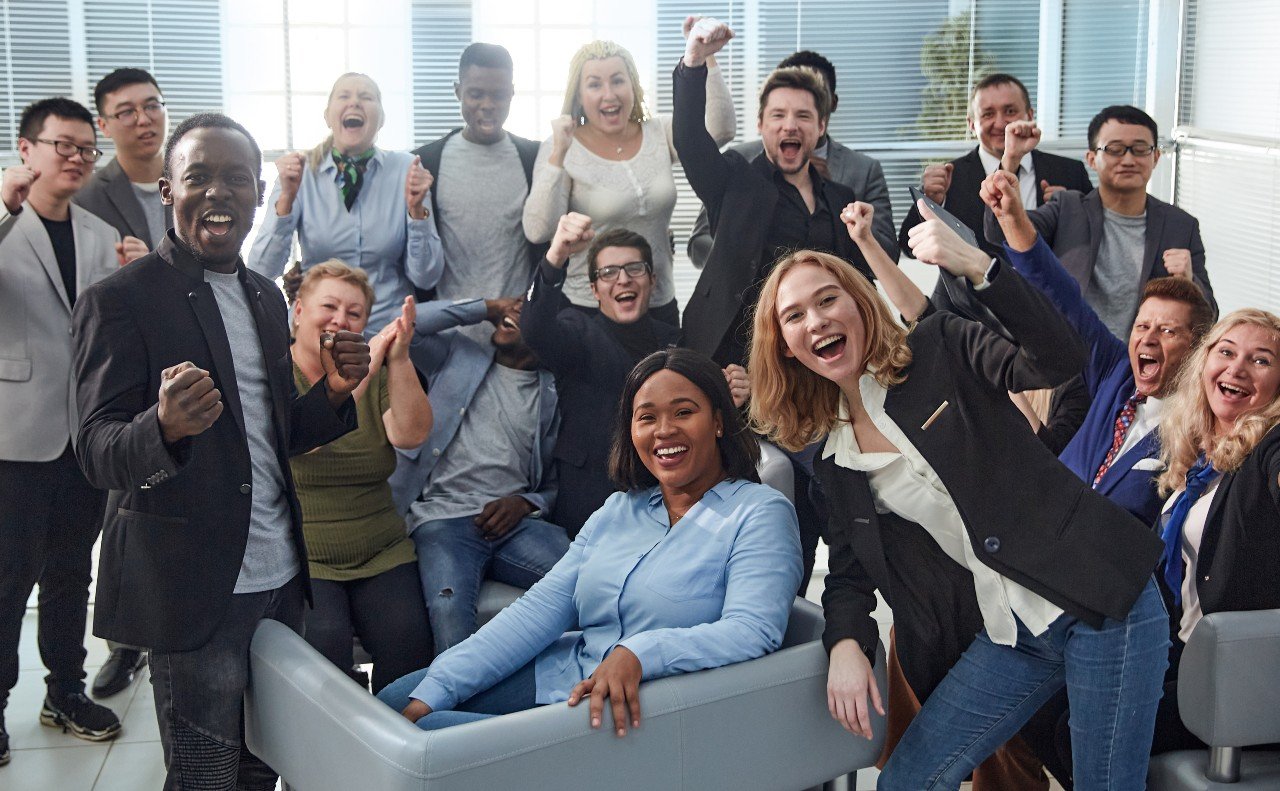 diverse office team smiles and cheers for the camera