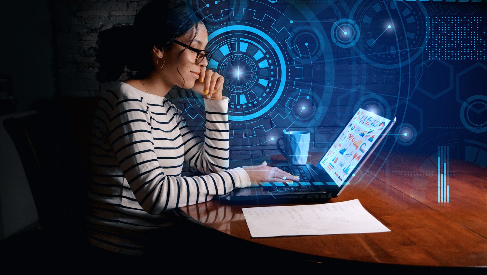 woman sitting at desk working on laptop with digital graphics surrounding her
