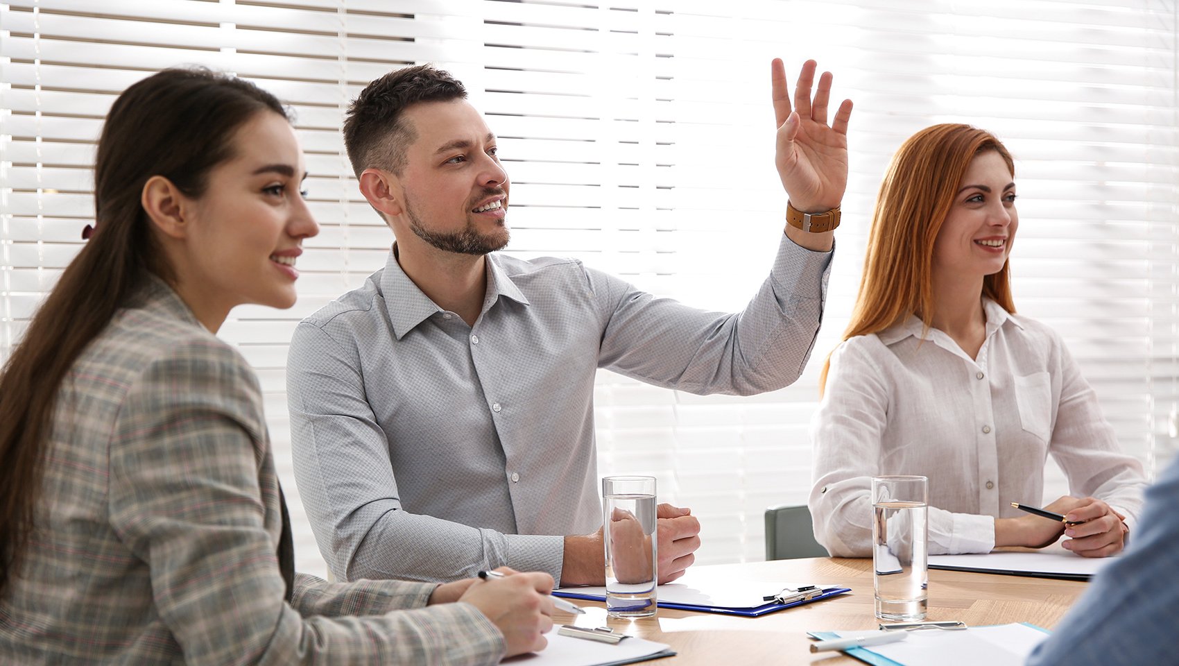 Man raising hand to ask question at business training in conference room