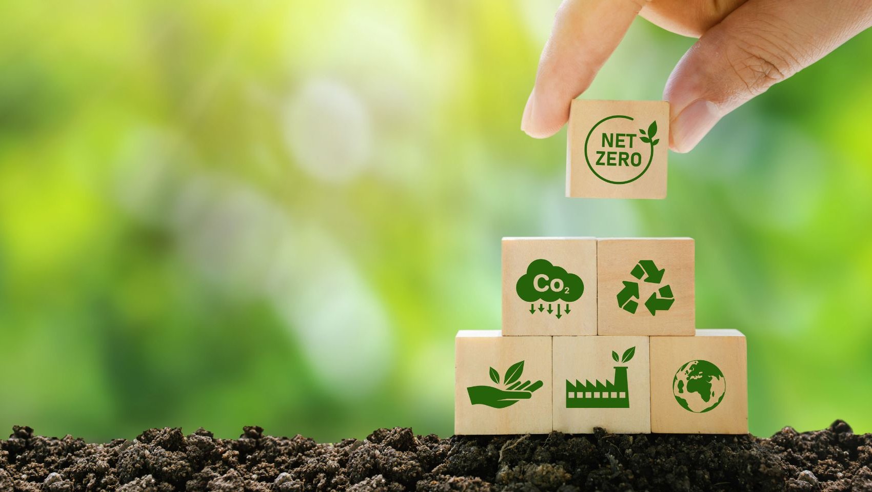 Net Zero and Carbon Neutral Concepts, Net Zero Emissions Goals, Ready to put wooden blocks by hand with green net center icon and green icon on wooden background.